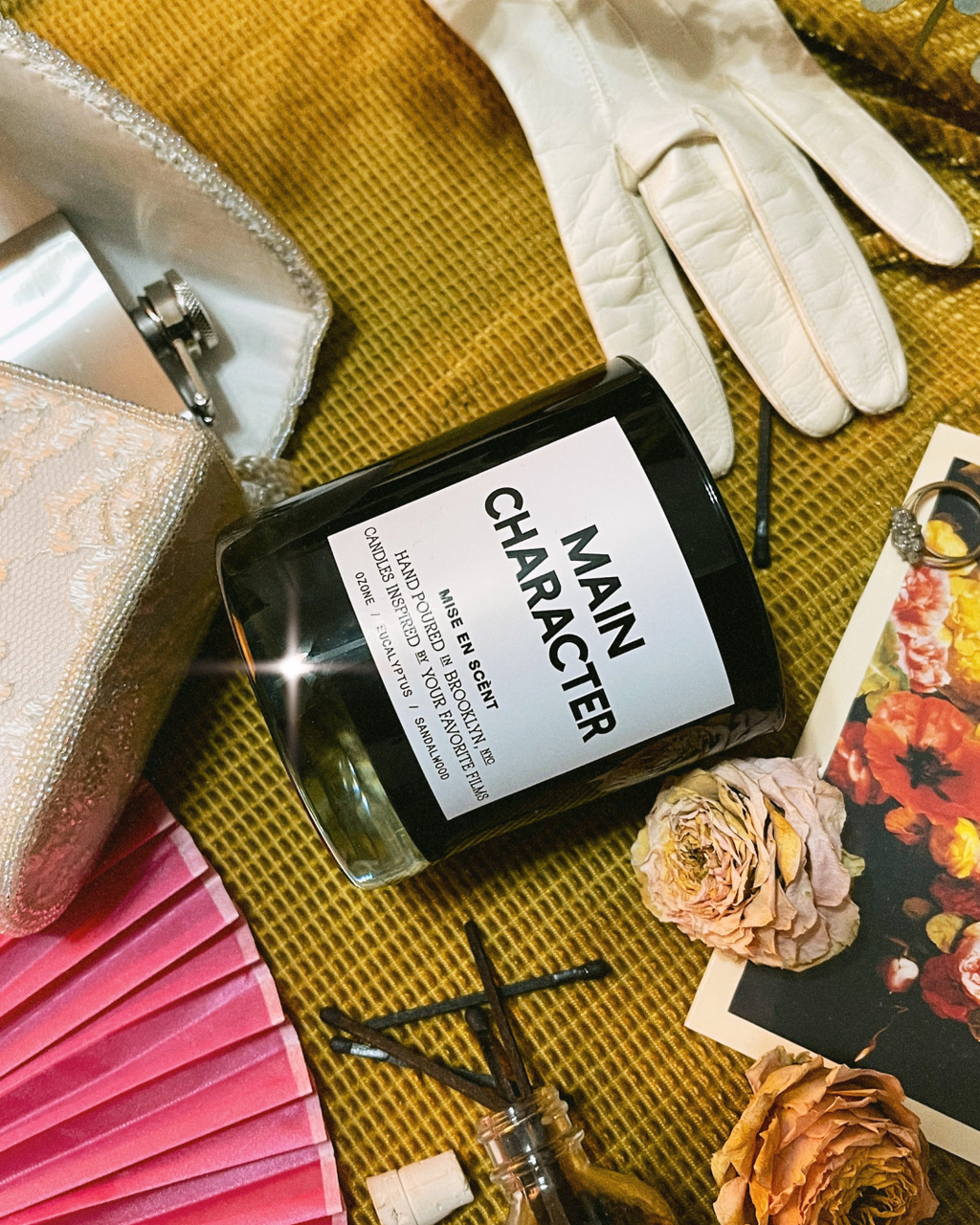 Main Character candle with white gloves, a pink fan, old photos and dried roses
