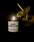 Main Character candle lit beside an anthurium in the dark