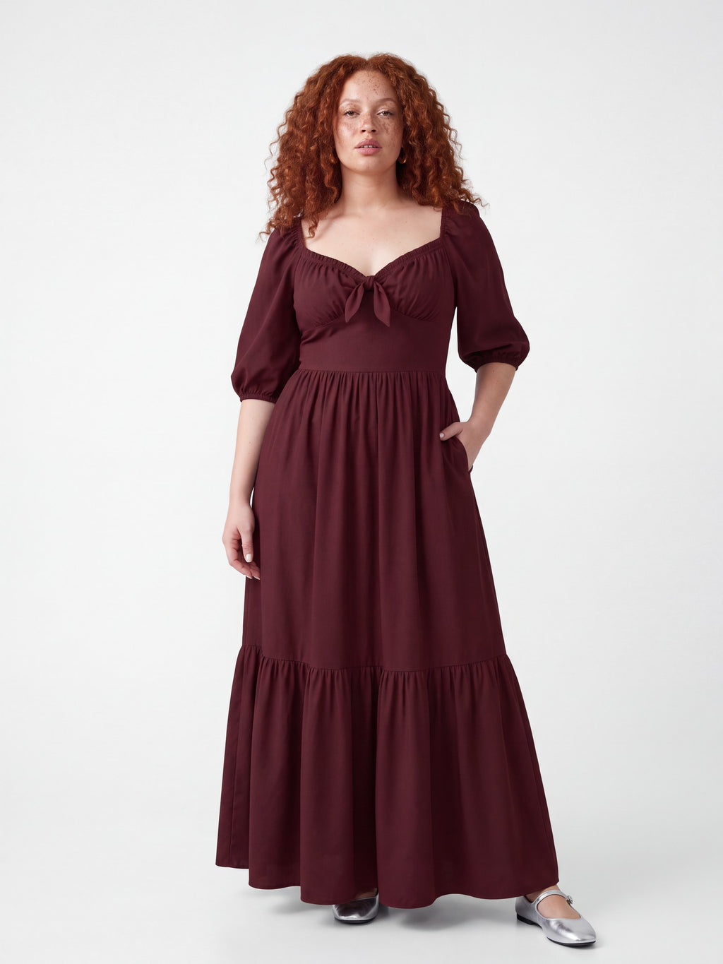 Model in the Molly 70s Maxi Gown in Burgundy, front view, showing the gathered sweetheart bodice, 3/4 puff sleeves and tiered floor-length skirt