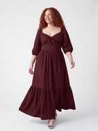 Model walking in the Molly 70s Maxi Gown in Burgundy, the tiered skirt swinging mid-stride