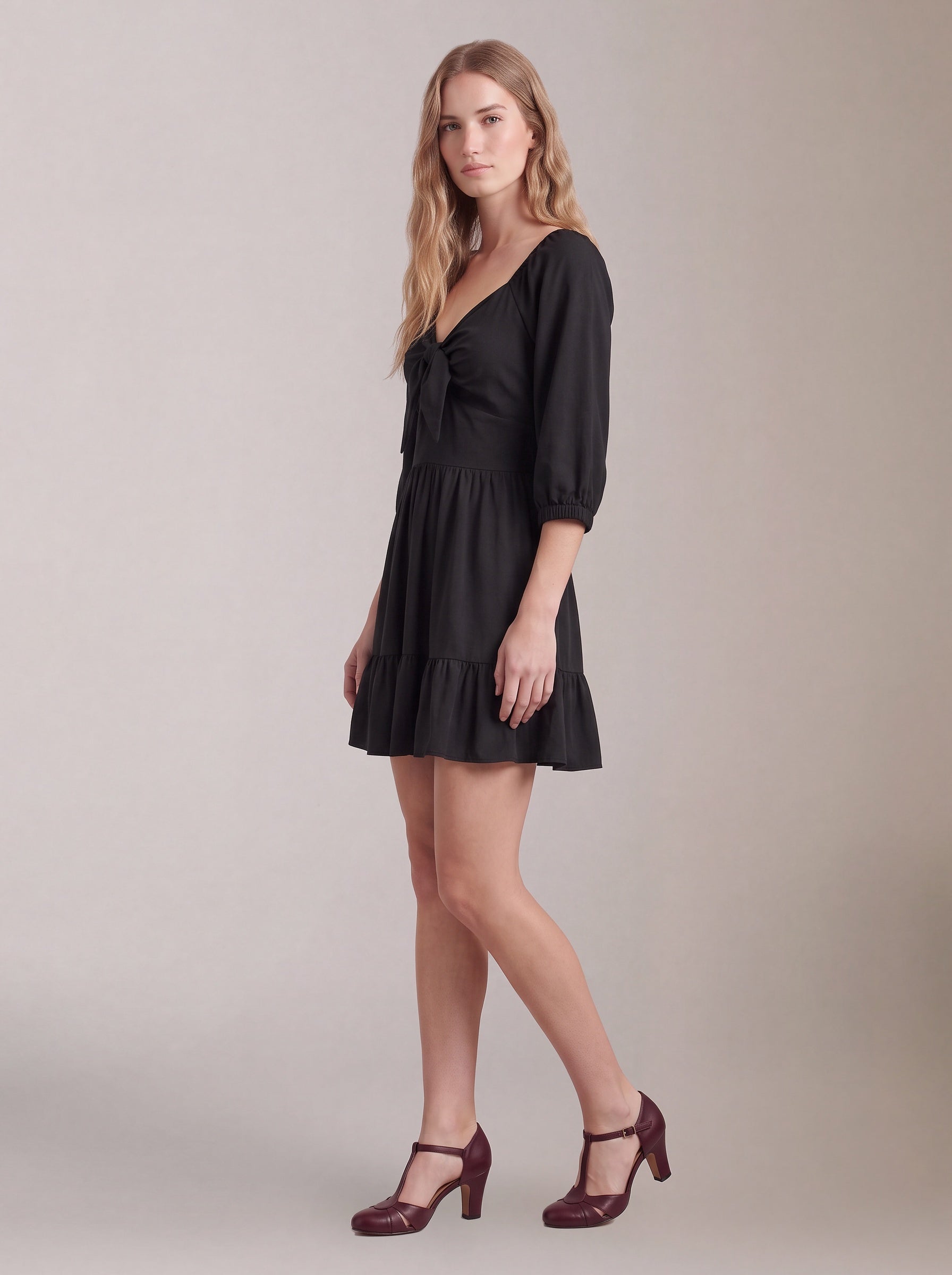 Molly Mini dress in solid black, three-quarter side view, showing the flared tiered skirt and elbow-length puff sleeves.