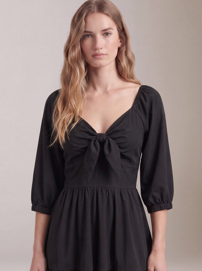 Close-up of the tie-front sweetheart bodice and elasticized sleeve cuffs on the black Molly Mini dress.