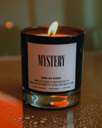 Mystery candle lit, in a black glass jar
