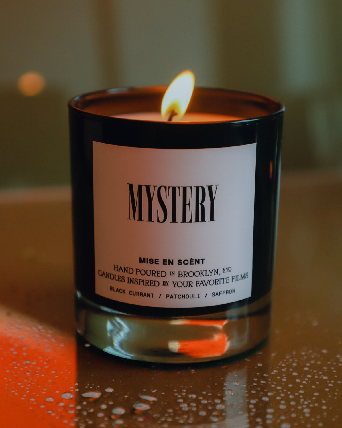 Mystery candle lit, in a black glass jar
