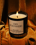Old Hollywood candle lit on gold fabric