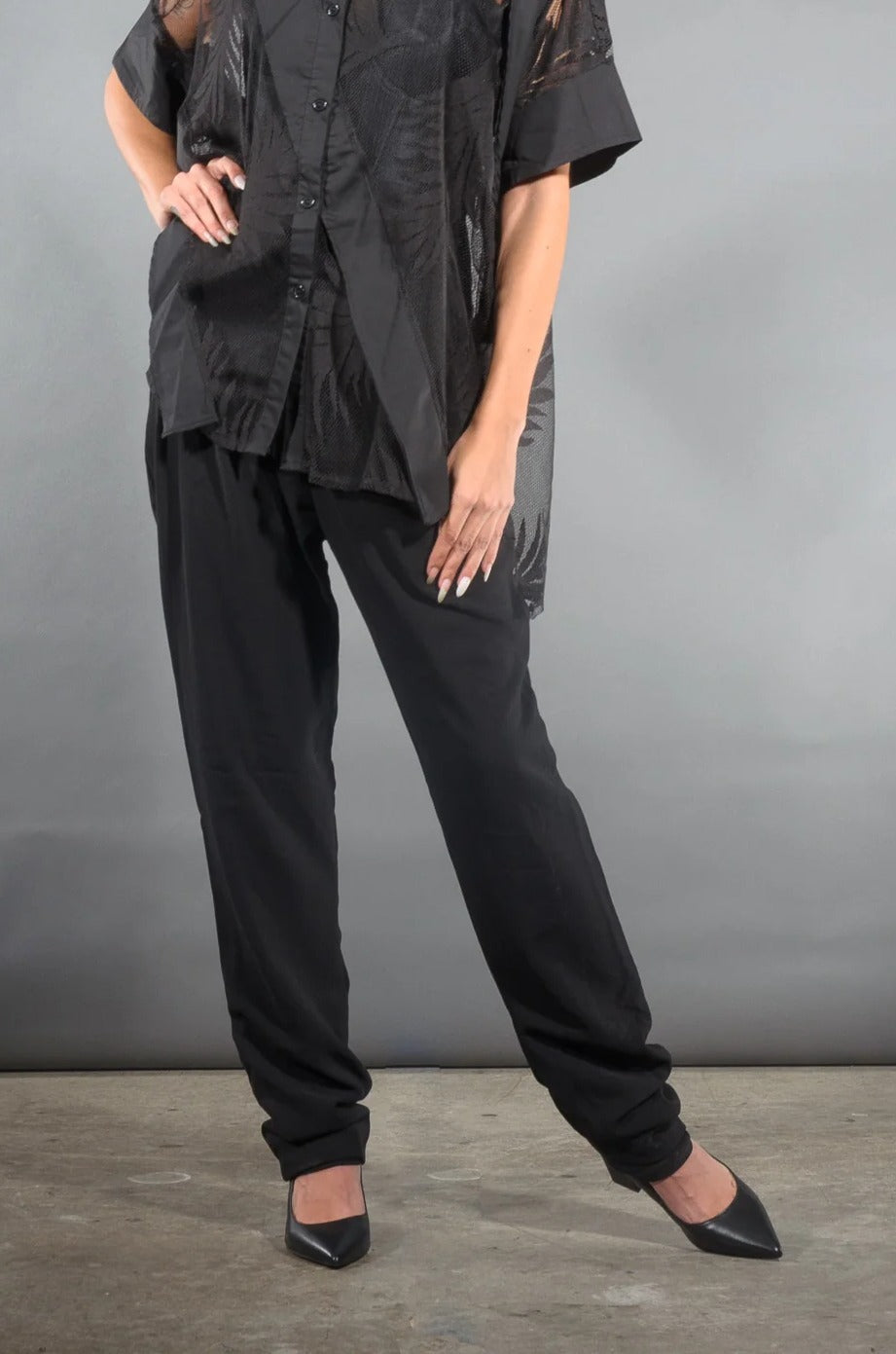 Waist-down view of the Olivia tapered pleat pants in black crepe with black pointed heels