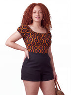 Model wearing the vintage peasant top in the orange and black Hotel Hexagon print, styled with LB high-waisted shorts in solid black
