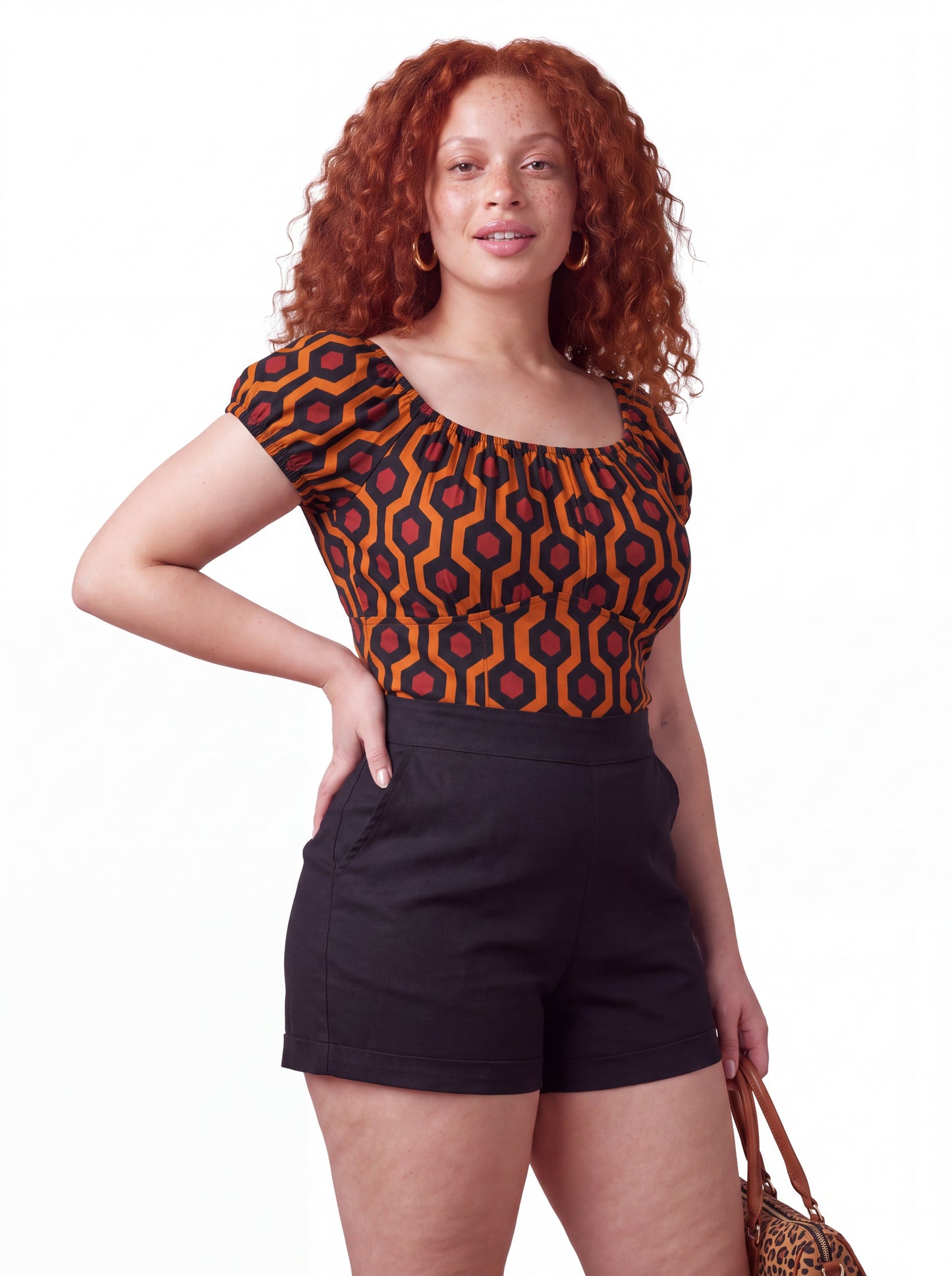 Model wearing the vintage peasant top in the orange and black Hotel Hexagon print, styled with LB high-waisted shorts in solid black