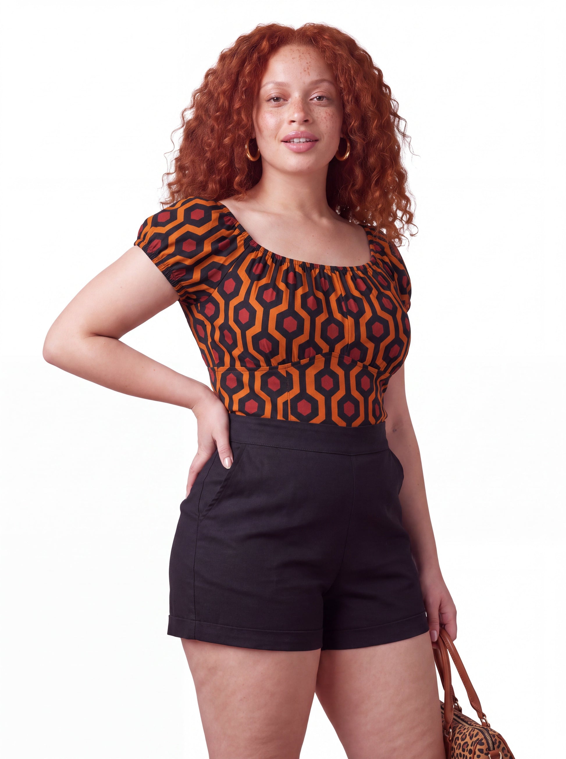 Model wearing the vintage peasant top in the orange and black Hotel Hexagon print, styled with LB high-waisted shorts in solid black