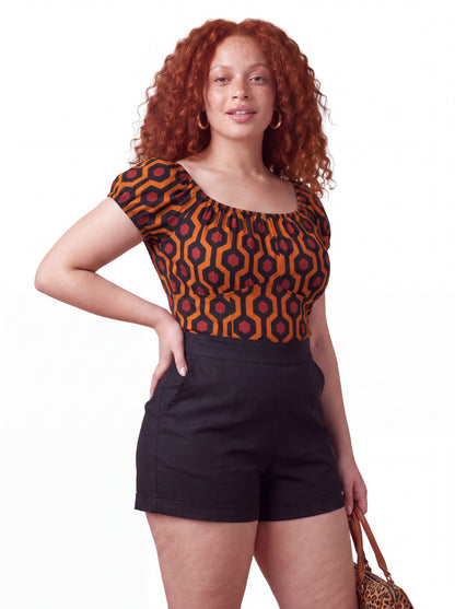 Model wearing the vintage peasant top in the orange and black Hotel Hexagon print, styled with LB high-waisted shorts in solid black