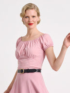 Model in the vintage peasant top in Pinup Girl Pink, gathered neckline and short puff sleeves, tucked into the matching pink Viva skirt with a black leather belt