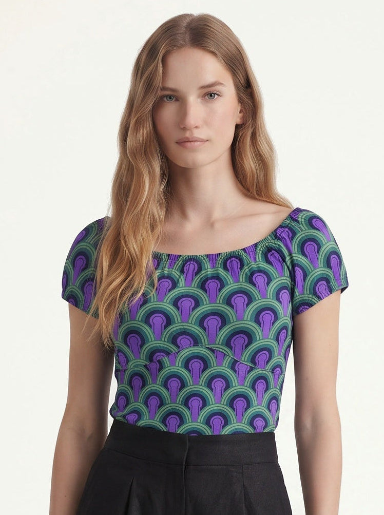 Close up of the vintage peasant top in the purple and green Room 237 print, gathered neckline worn on the shoulders, with black trousers