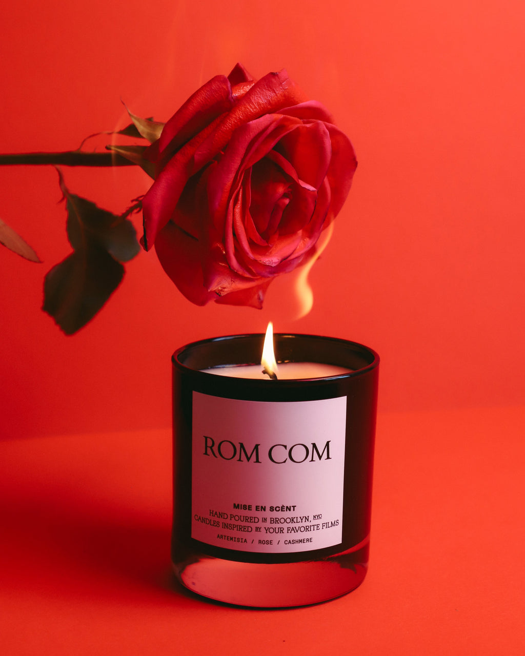 Rom Com candle lit beneath a red rose
