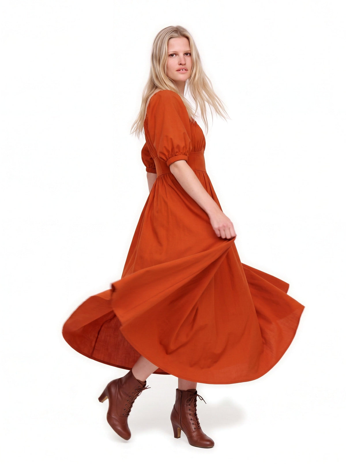 Amber Harvest Swann Maxi Dress mid-turn, the full deep spiced orange skirt flying out over brown lace-up boots