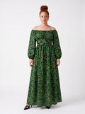 Model wearing the Swann Maxi Dress in Black Serpente, green foliage and gold snakes on black, off the shoulder with long blouson sleeves, floor length