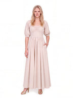 Swann Maxi Dress in Coconut Milk, a warm off-white floor-length maxi with a gathered square neckline worn up on the shoulders, puffed elbow-length sleeves and a fitted waistband