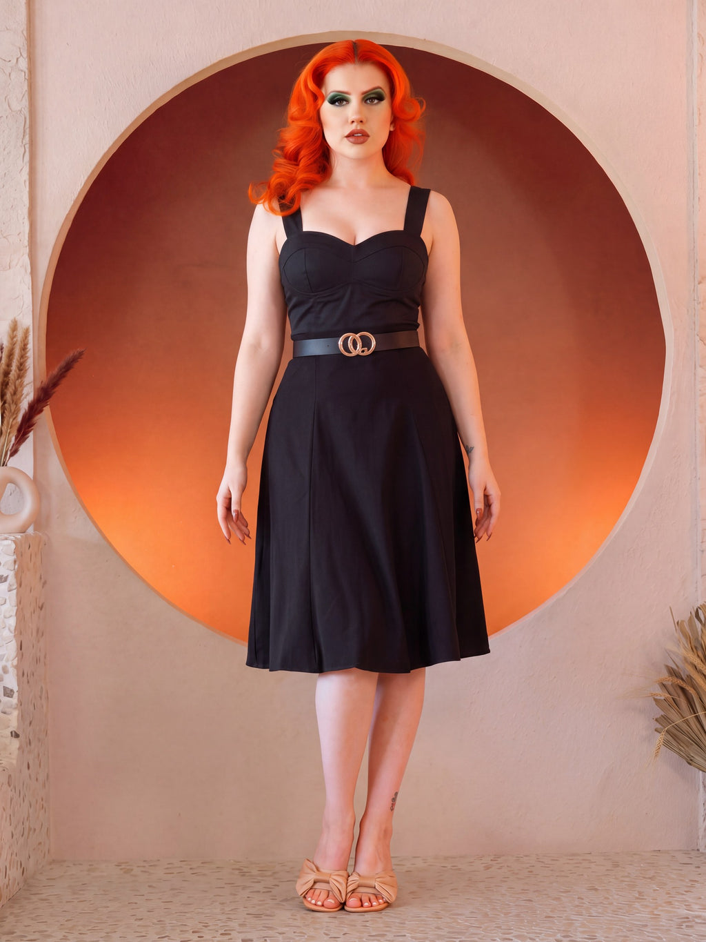 Front view of the Varla Top in Black with the Viva 40s Tulip Skirt in Black, the paneled skirt flaring from a belted waist to just below the knee, worn with tan bow sandals