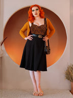 Model in the Varla Top in Hotel Hexagon, the orange and black hexagon bullet top with a sweetheart neckline, styled with the black Viva Tulip Skirt and a mustard cardigan