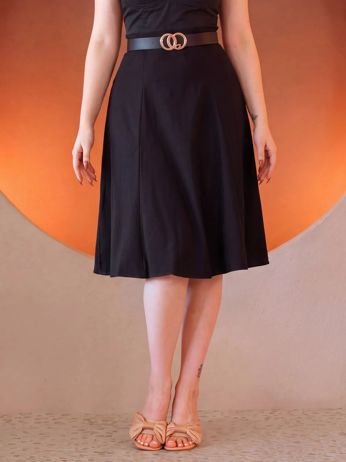 Viva 40s Tulip Skirt in Black from the waist down, high waist with a gold ring belt, paneled skirt flaring to just below the knee, worn with tan bow sandals