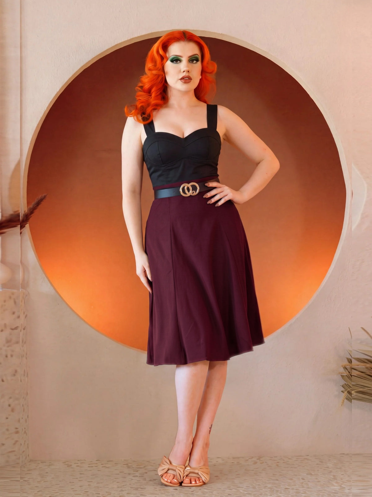 Model in the Viva 40s Tulip Skirt in Burgundy, hand on hip, showing the high waist and the flare of the paneled skirt