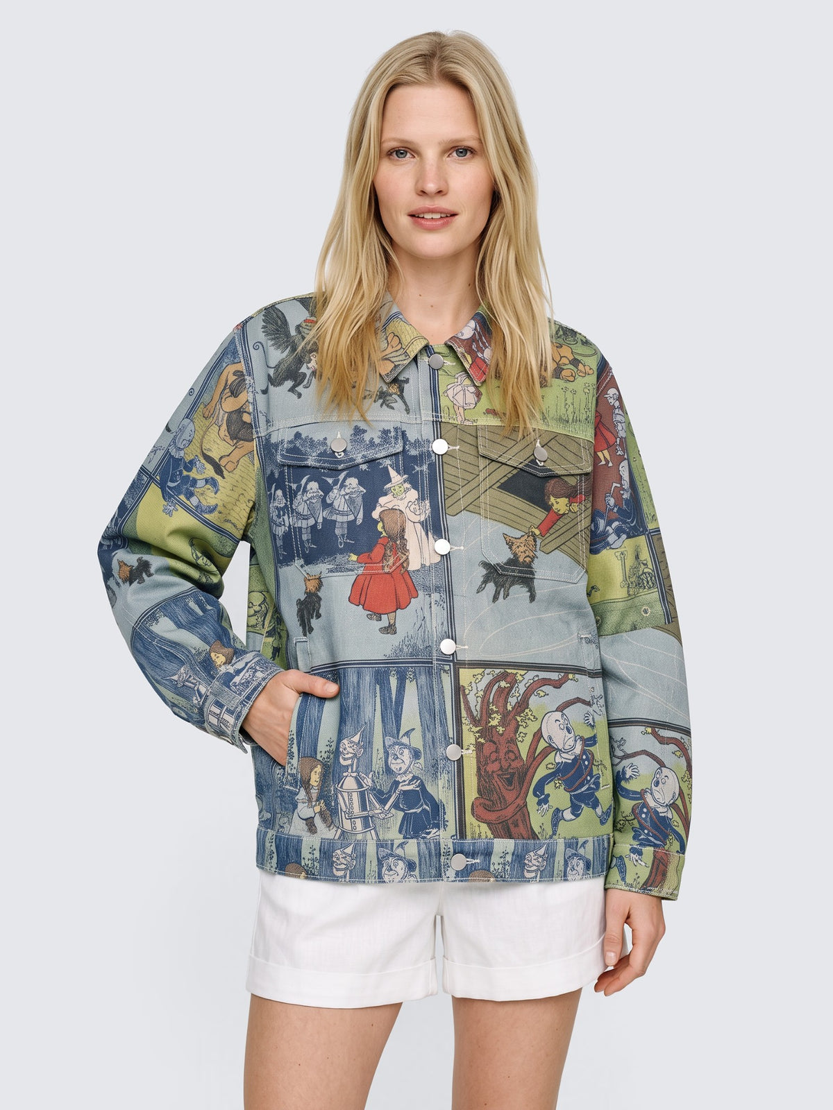 Model with one hand in the pocket of the oversized Wizard of Oz Denim Jacket, buttoned, worn with white high-waisted shorts