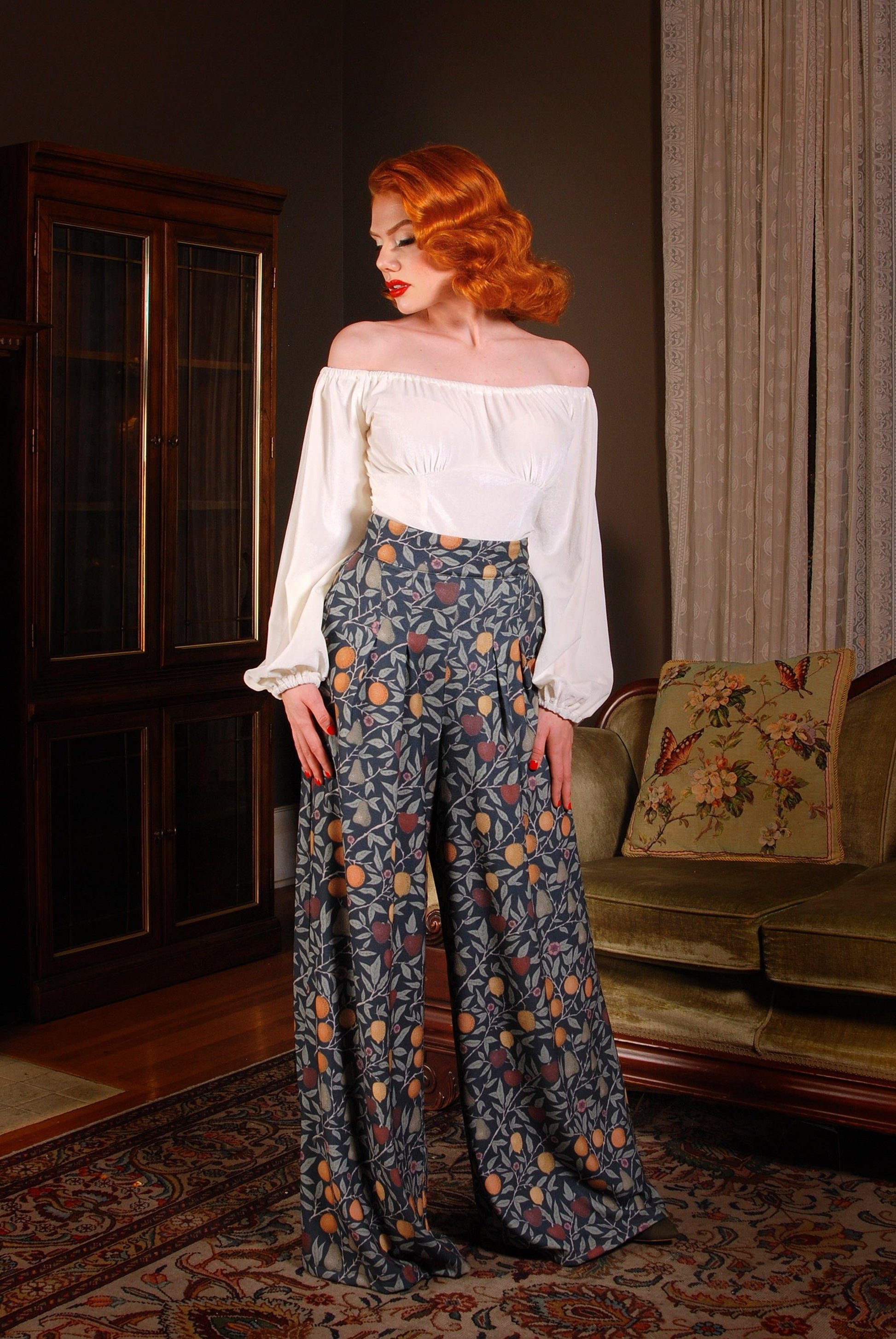 Pinup Girl Clothing models Cora Morgan and Seattle pose in the PUG favorite Dietrich vintage inspired wide leg palazzo pants with pockets made of high quality stretch crepe in the exclusive Laura Byrnes and Hope Morrison Night in Eden Fruit Print.